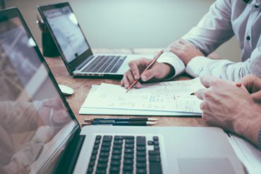 deux collègues travaillent autour de deux ordinateurs et une feuille de papier