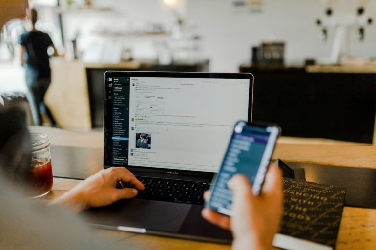 Un salarié au bureau devant son MacBook Pro et son smartphone