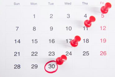Calendrier avec des punaises rouges indiquant des dates importantes