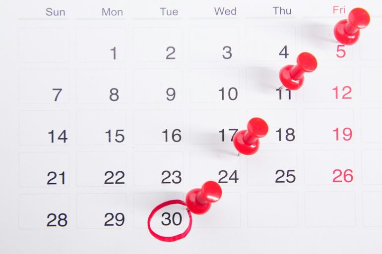Calendrier avec des punaises rouges indiquant des dates importantes
