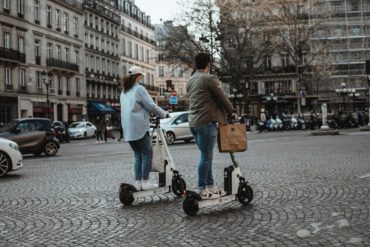 Deux personnes effectuent un trajet en ville avec une trottinette
