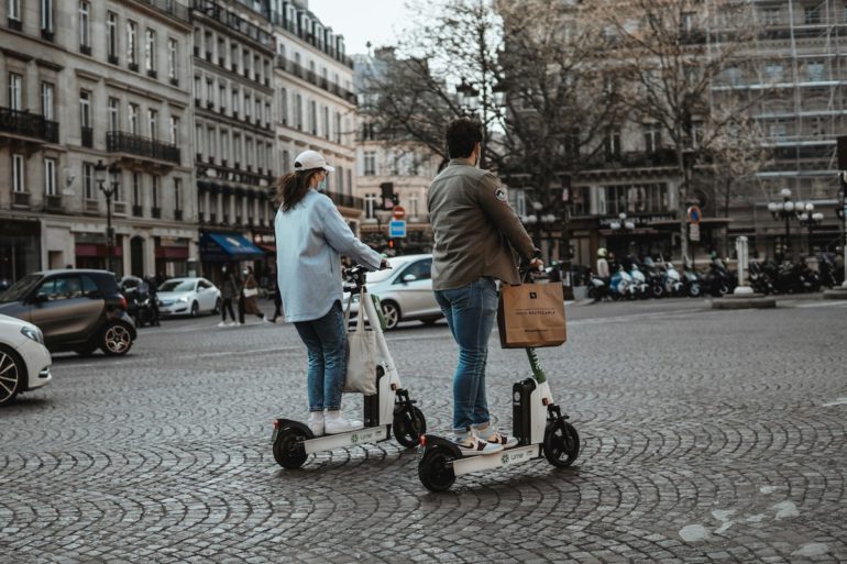 Deux personnes effectuent un trajet en ville avec une trottinette